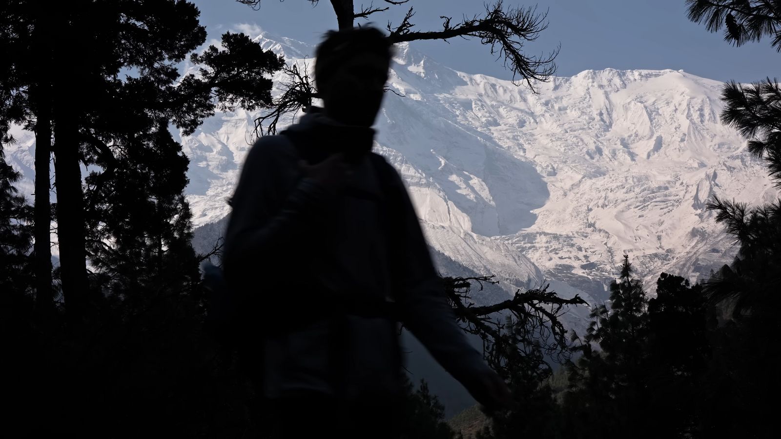 a man with a backpack standing in front of a mountain