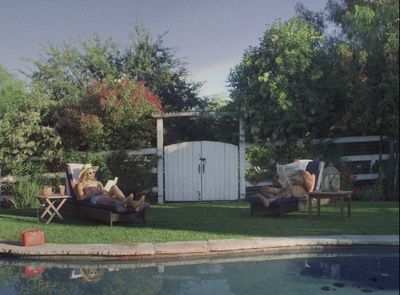 a woman laying on a lawn chair next to a pool