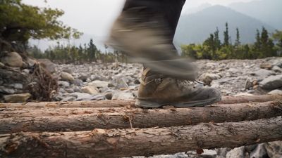 a person walking on a log in a rocky area