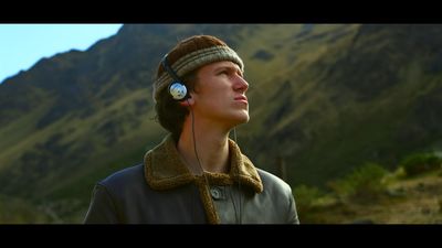 a young man wearing headphones standing in front of a mountain