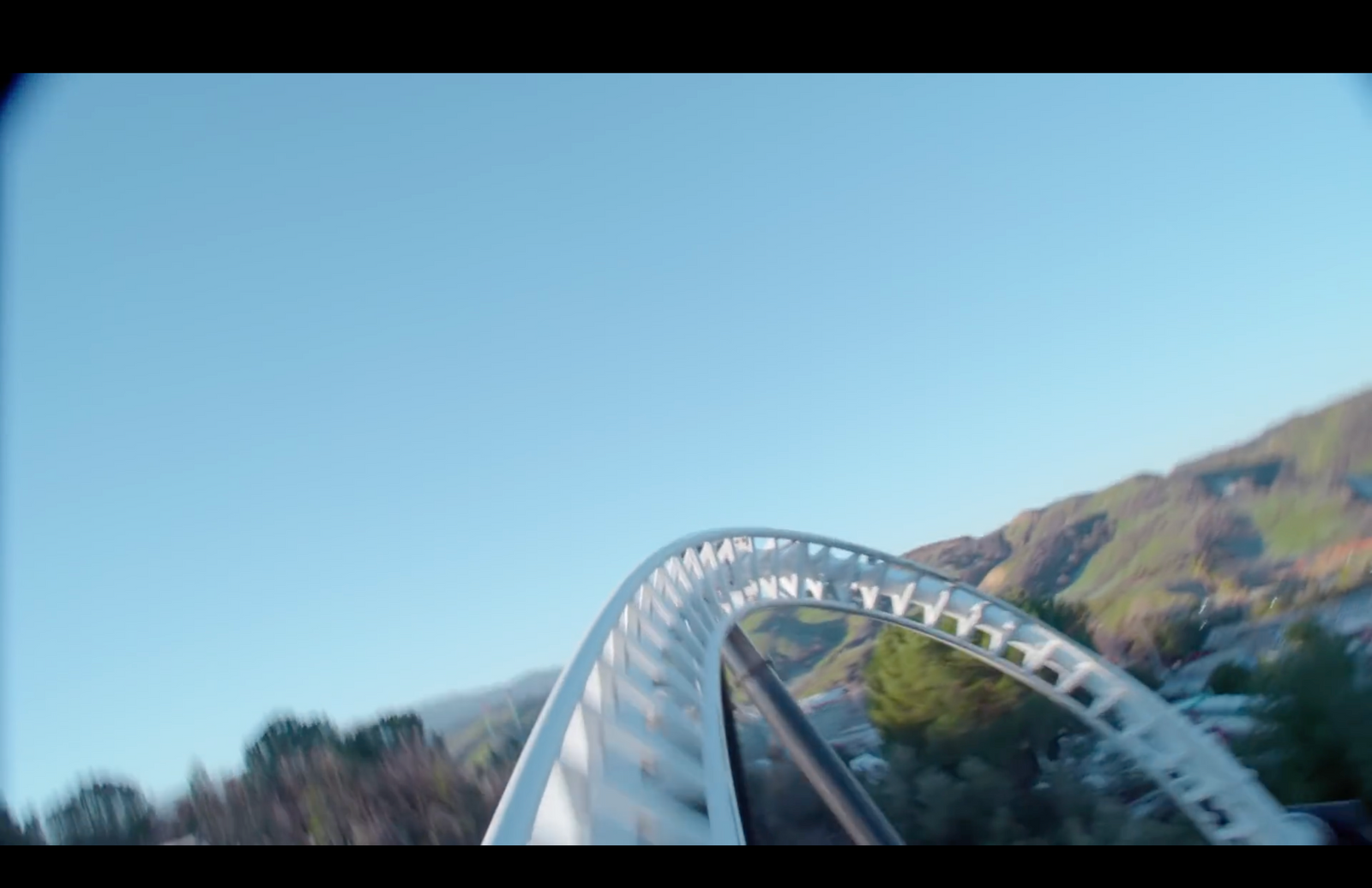 a roller coaster going down a hill with a mountain in the background