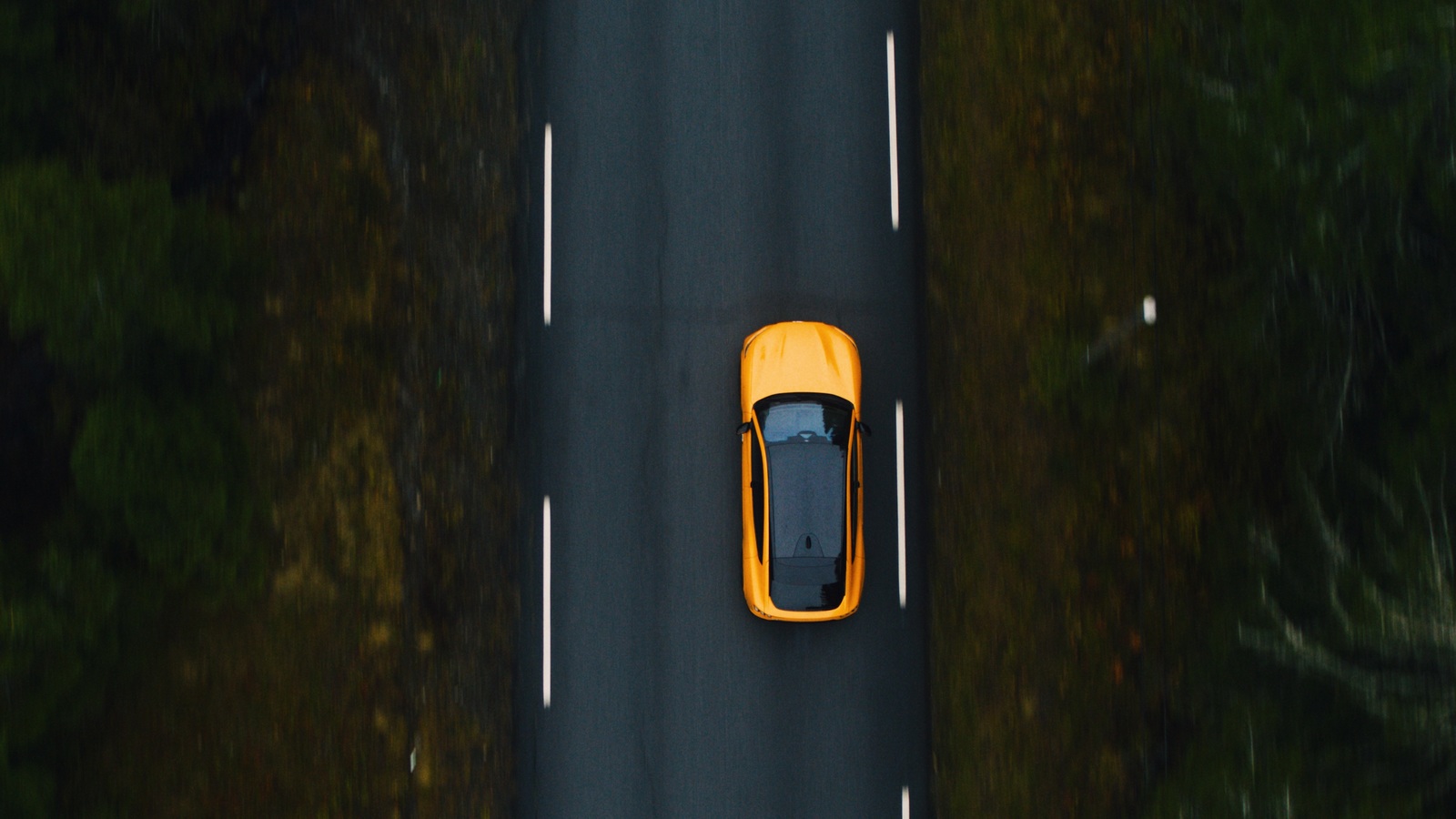 a yellow sports car driving down a road