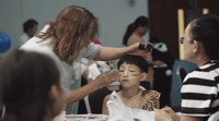 a young boy getting his make - up done by a woman