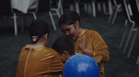 a couple of people standing next to a blue ball