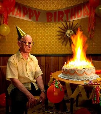 a man sitting in front of a birthday cake