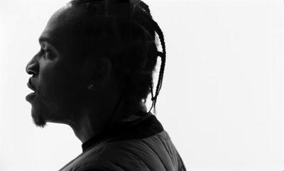 a black and white photo of a man with dreadlocks