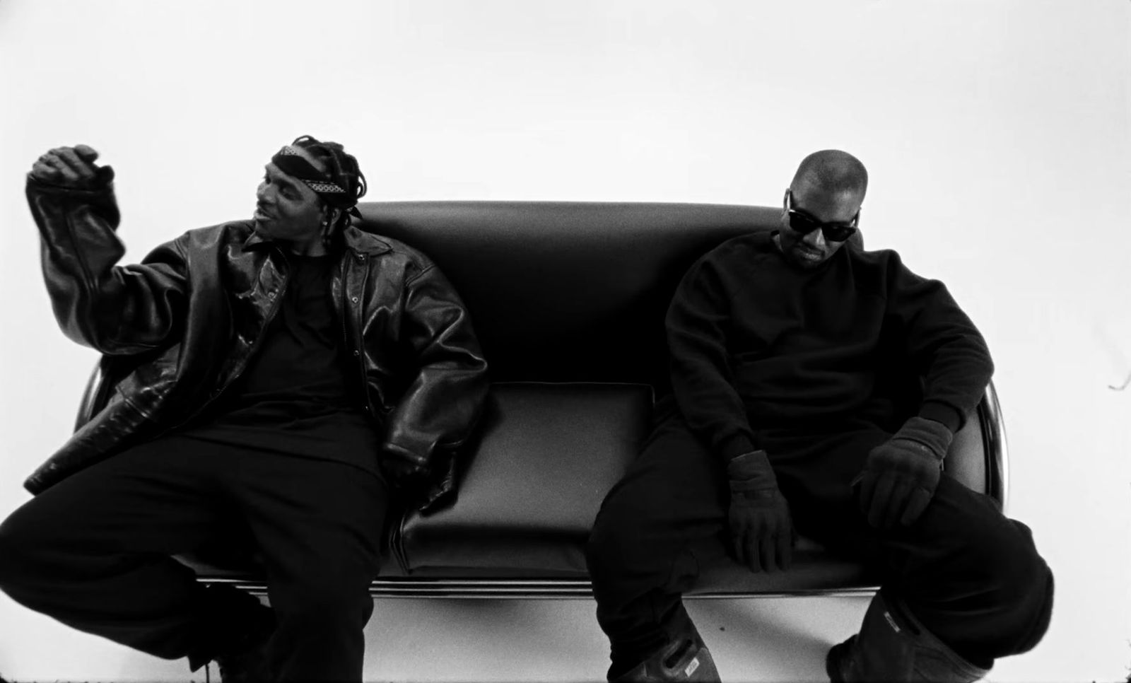 a black and white photo of two men sitting on a couch