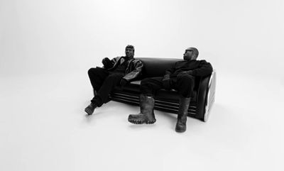 a couple of men sitting on top of a black couch