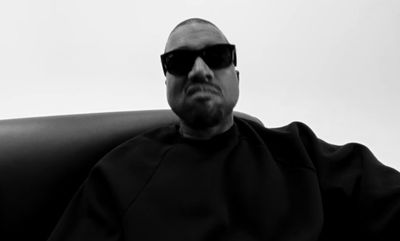 a bald man wearing sunglasses sitting in a chair