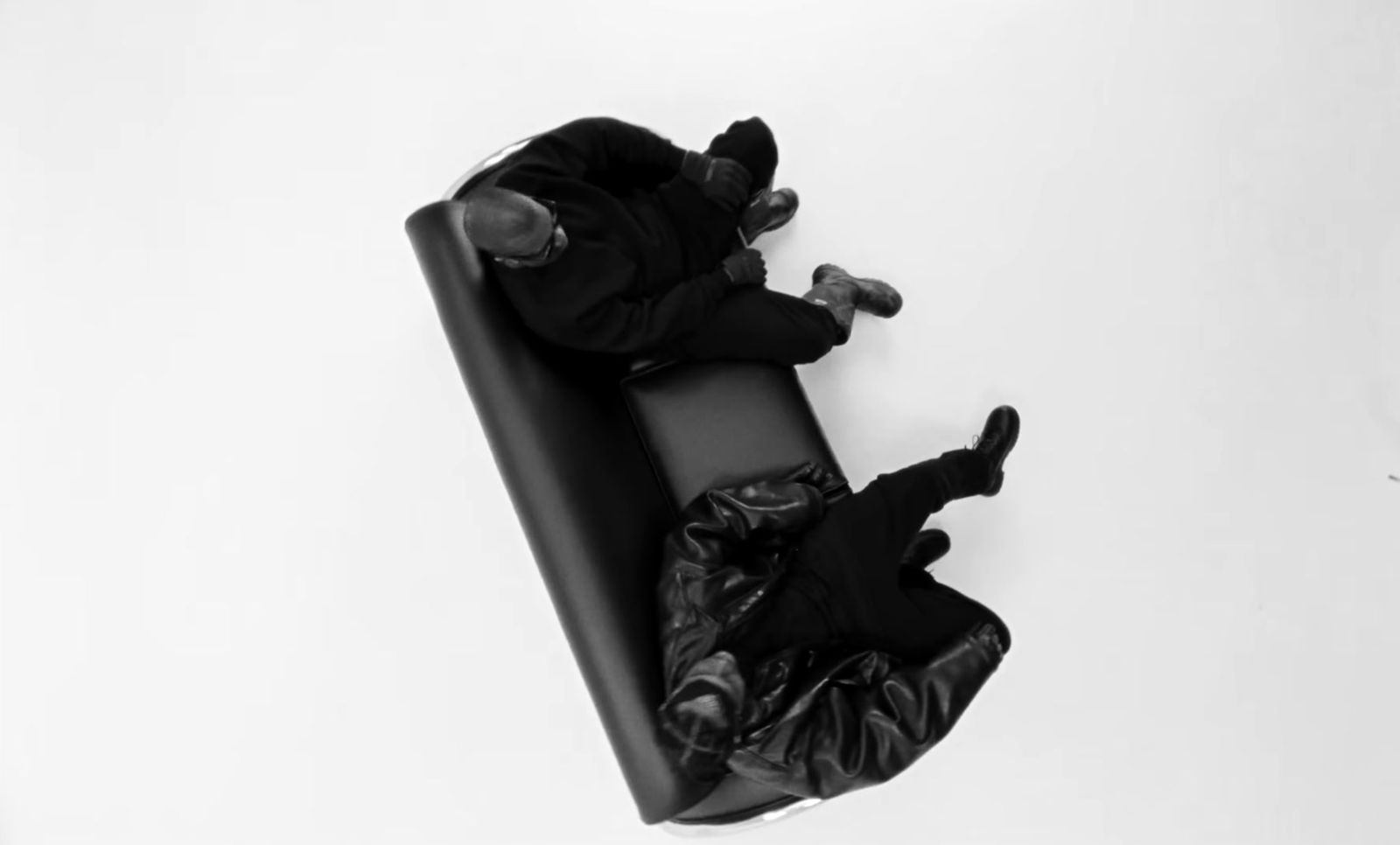 a couple of people laying on top of a black couch