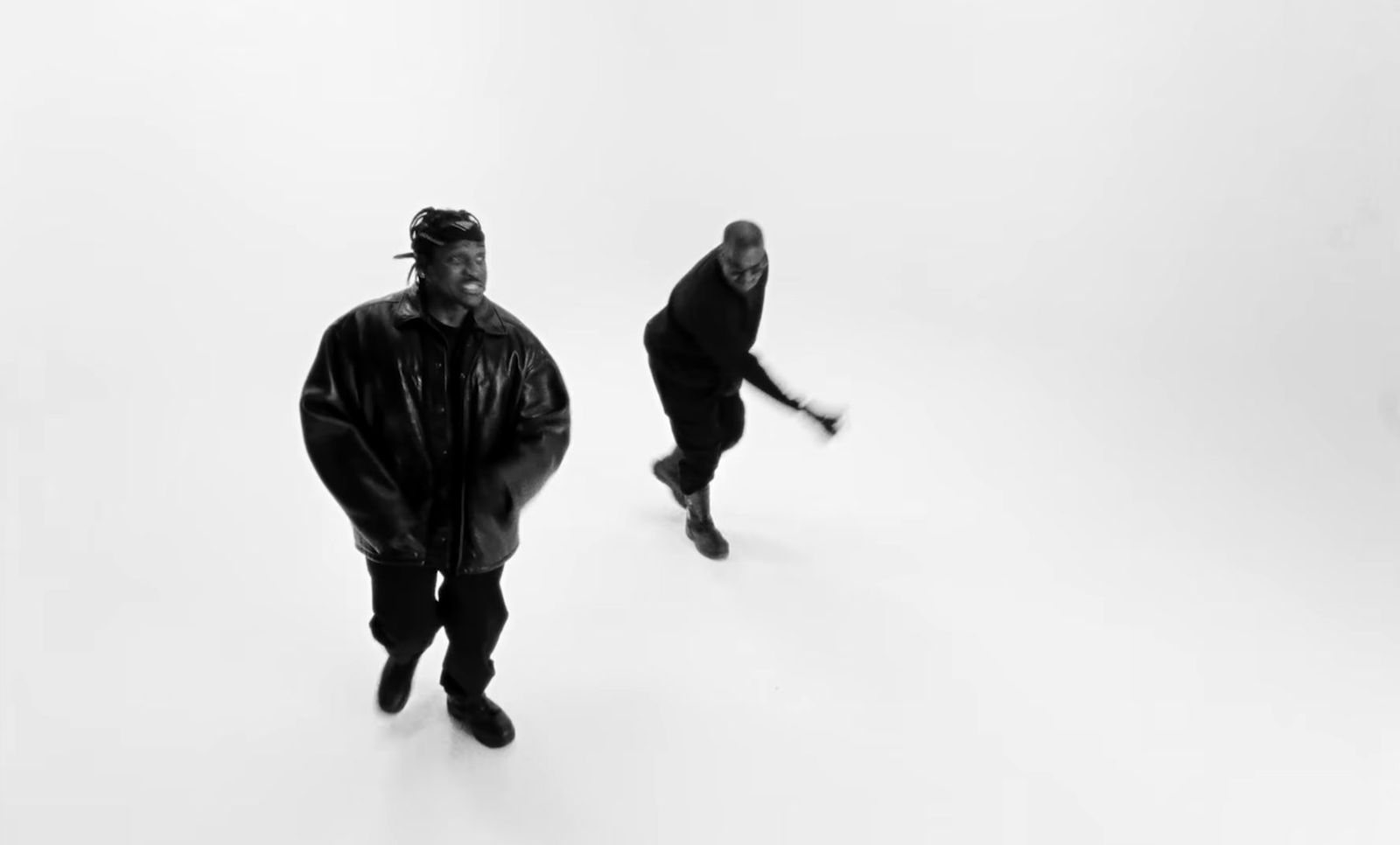 two men in black clothing standing in a white room