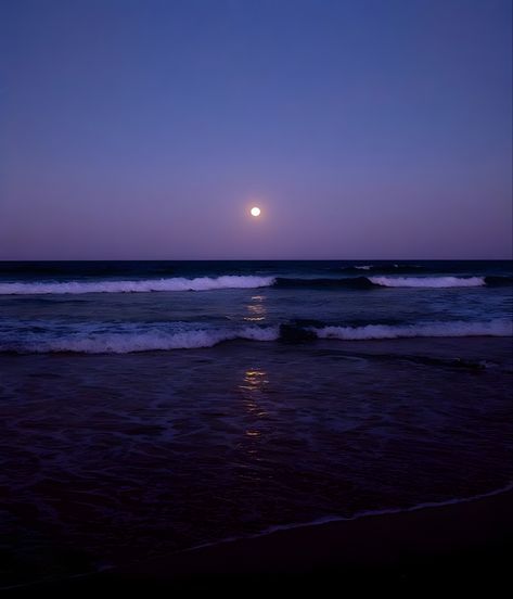 a full moon rising over the ocean with waves