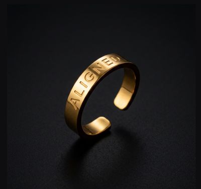 a gold ring with the word alone engraved on it