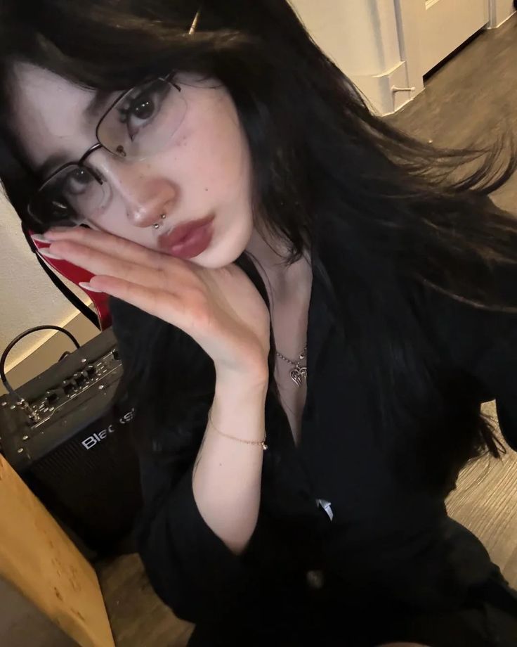 a woman with glasses sitting on the floor