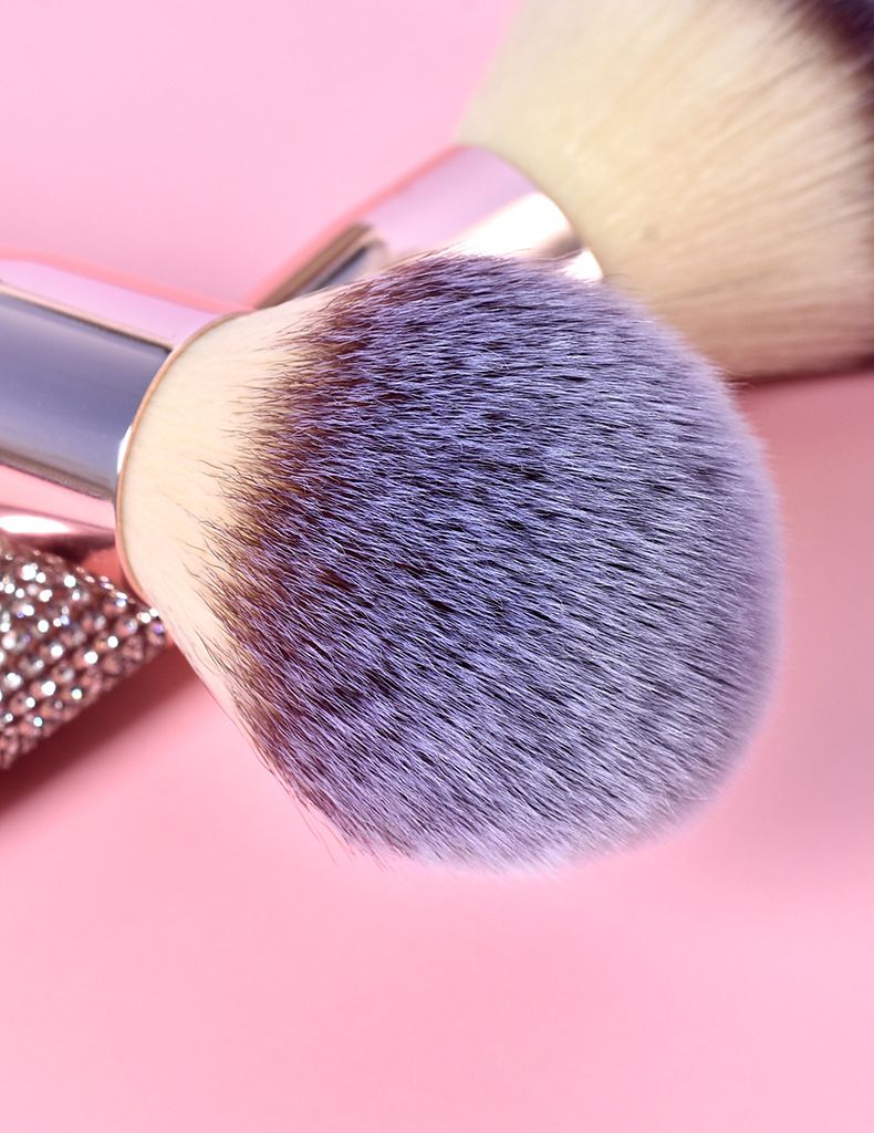 a close up of a makeup brush on a pink background