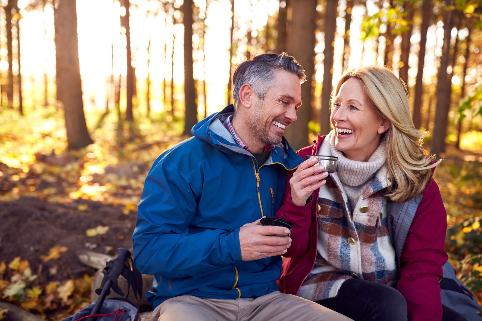 a man and woman sitting on a bench in the woods