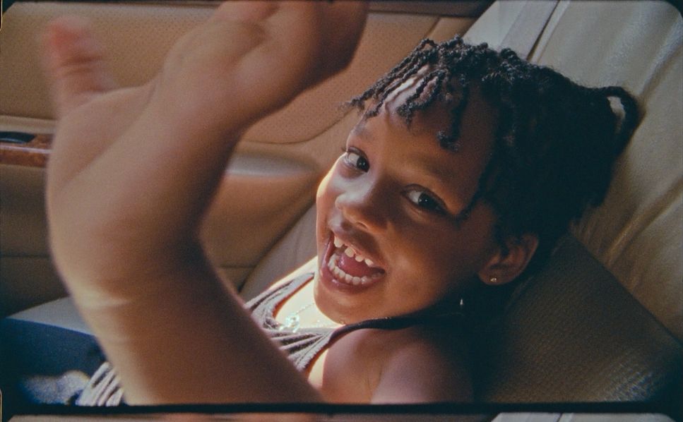 a woman sitting in a car with her hand up in the air