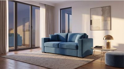 a blue couch sitting in a living room next to a window