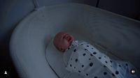 a baby laying in a white crib with a black polka dot blanket