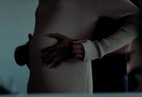 a woman in a white sweater holding her stomach