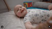 a baby laying on a bed with a toy