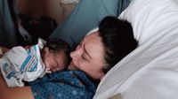 a woman holding a baby in a hospital bed