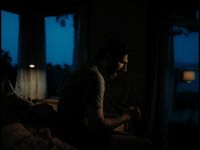 a man sitting on a bed in a dark room