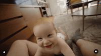 a baby is smiling while sitting on the floor