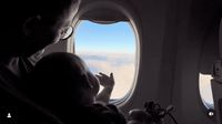 a man holding a baby looking out an airplane window