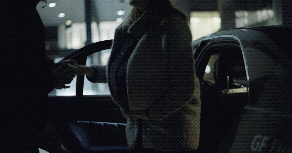 a woman standing next to a car talking on a cell phone
