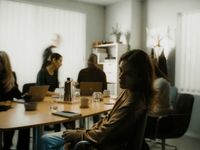 a group of people sitting around a table with laptops