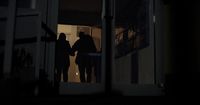 a couple of people standing outside of a house at night