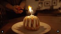 a person lighting a candle on top of a cake