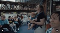 a group of people sitting on a bus with a bridge in the background