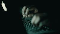 a person typing on a keyboard in the dark