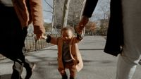 a little girl walking down the street with her parents