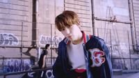 a boy in a blue jacket standing in front of a wall