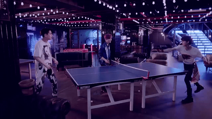 a group of people standing around a ping pong table