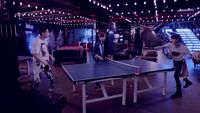 a group of people standing around a ping pong table