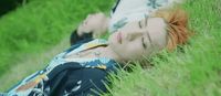 a woman laying in the grass with her eyes closed