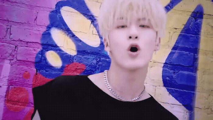 a man with blonde hair standing in front of a graffiti wall