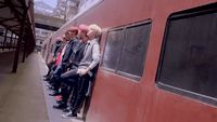 a group of people standing on the side of a train