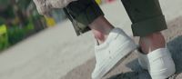 a person wearing white shoes and a furry coat