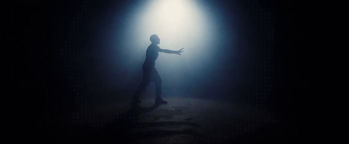 a man standing in the dark with his arms outstretched