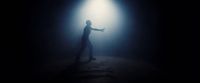 a man standing in the dark with his arms outstretched