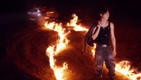 a woman standing in front of a bunch of fire