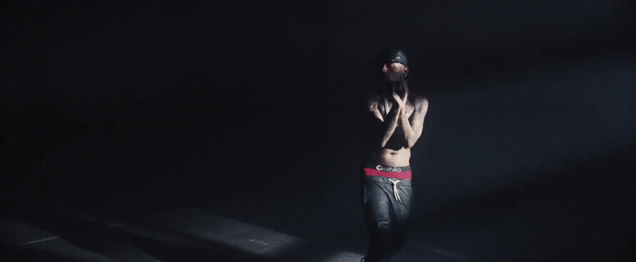 a shirtless man standing in a dark room