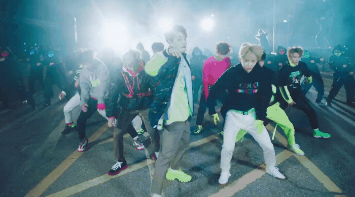 a group of young men dancing in a parking lot