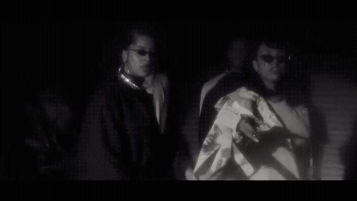two men standing next to each other in the dark
