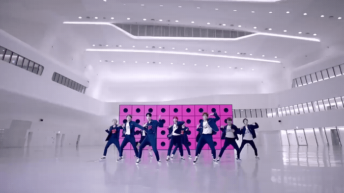 a group of young men standing in front of a pink wall
